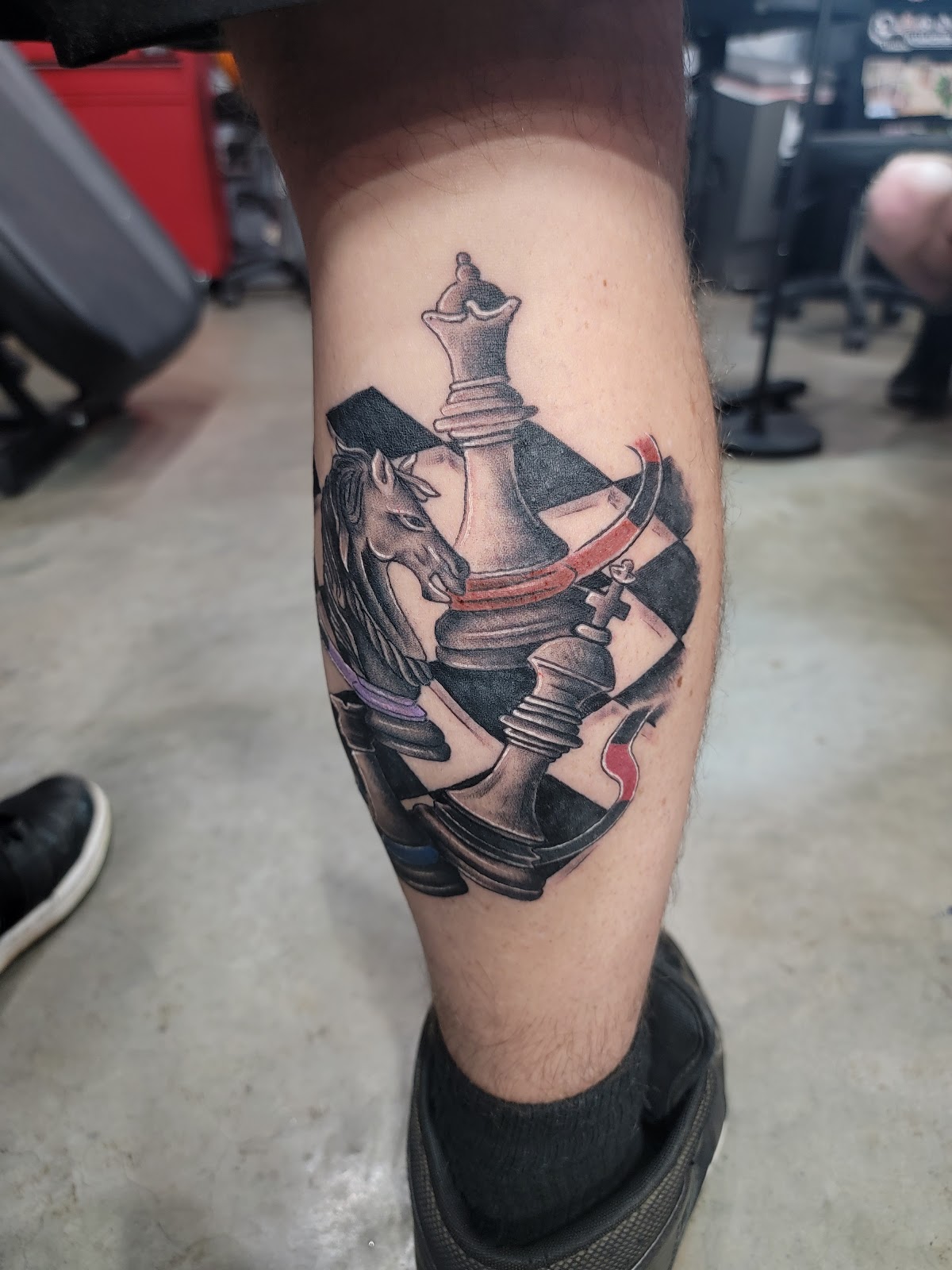 Color chess-piece tattoo with red ribbon detail